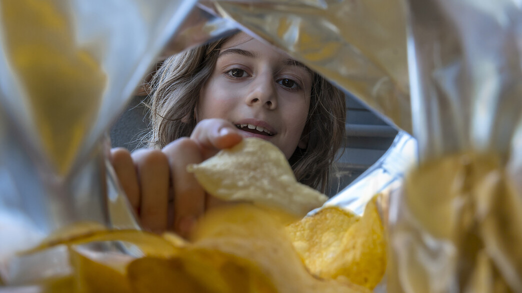 ילד אוכל חטיף צ'יפס מחבילה