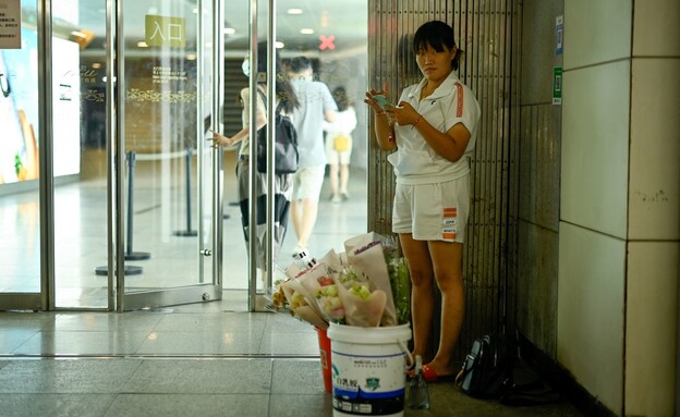 אישה מוכרת פרחים בבניין משרדים בבייג'ין, כלכלת סין (צילום: AFP, getty images)