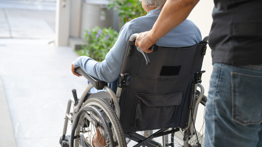 קשישה על כיסא גלגלים עם מטפל | אילוסטרציה