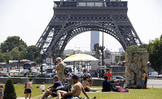 אנשים משתזפים סמוך למגדל אייפל בגל החום בצרפת (צילום: רויטרס)