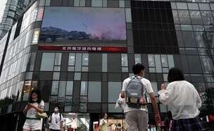 אנשים צופים בתרגיל הצבאי של סין נגד טייוואן (צילום: NOEL CELIS/AFP via Getty Images)