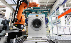 רובוט מרכיב מכונת כביסה במפעל BSH בגרמניה (צילום: Andreas Rentz, Getty Images)