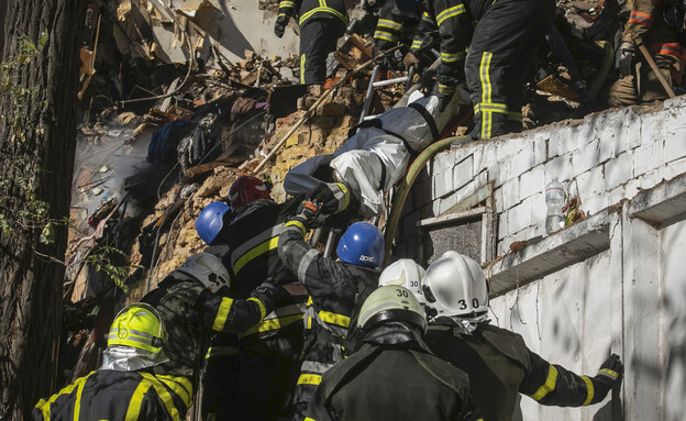 לוחמי אש מחלצים מבניין גופה של אדם הנהרג בהפצצות ה (צילום: AP)