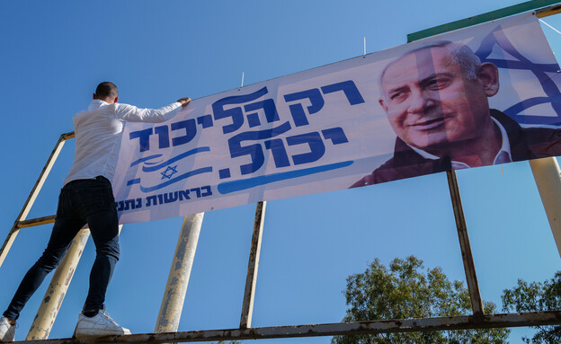 תומך ליכוד תולה שלט בבחירות 2022 (צילום: מיכאל גלעדי, פלאש 90)