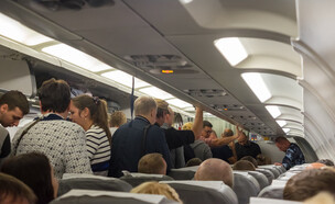 נוסעים עומדים במטוס (צילום: Aleksandr Shilov, shutterstock)