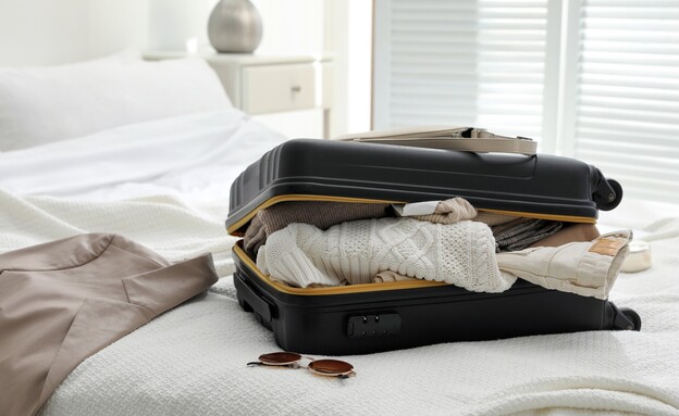מזוודה על מיטה (צילום: shutterstock)