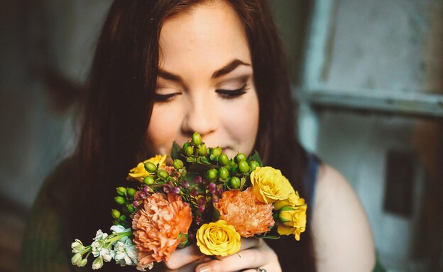 אישה מריחה פרחים (צילום: unsplash)