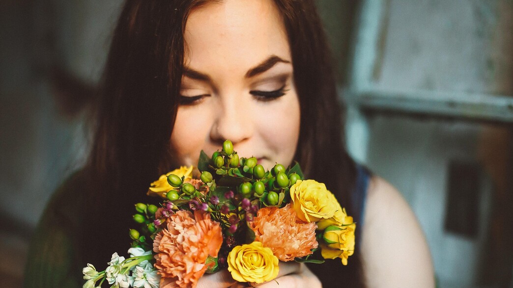 אישה מריחה פרחים