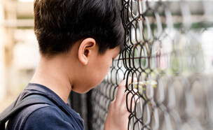 ילד משעין ראש על גדר (אילוסטרציה: myboys.me, shutterstock)
