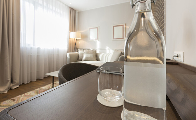 בקבוק מים בחדר המלון (צילום: Edvard Nalbantjan, shutterstock)