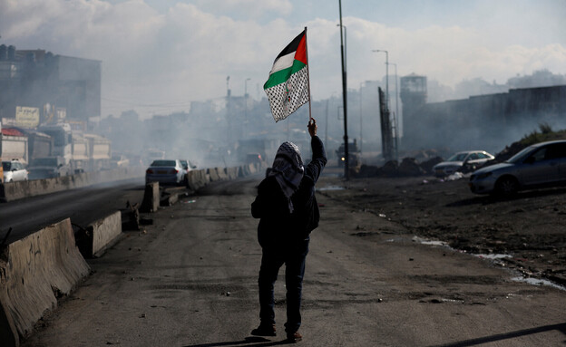 פלסטיני מניף את דגל פלסטין בעימותים עם כוחות צה"ל (צילום: רויטרס)