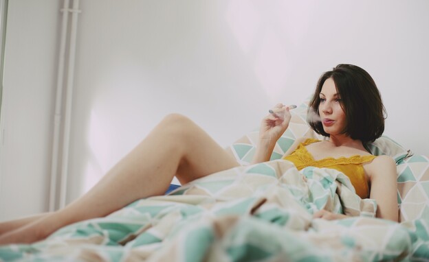 אישה מעשנת קנאביס במיטה (צילום: Elsa Donald, unsplash)