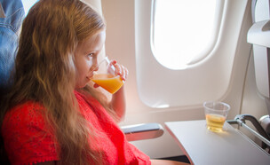 ילדה שותה מיץ תפוזים במטוס (צילום: TravnikovStudio, shutterstock)