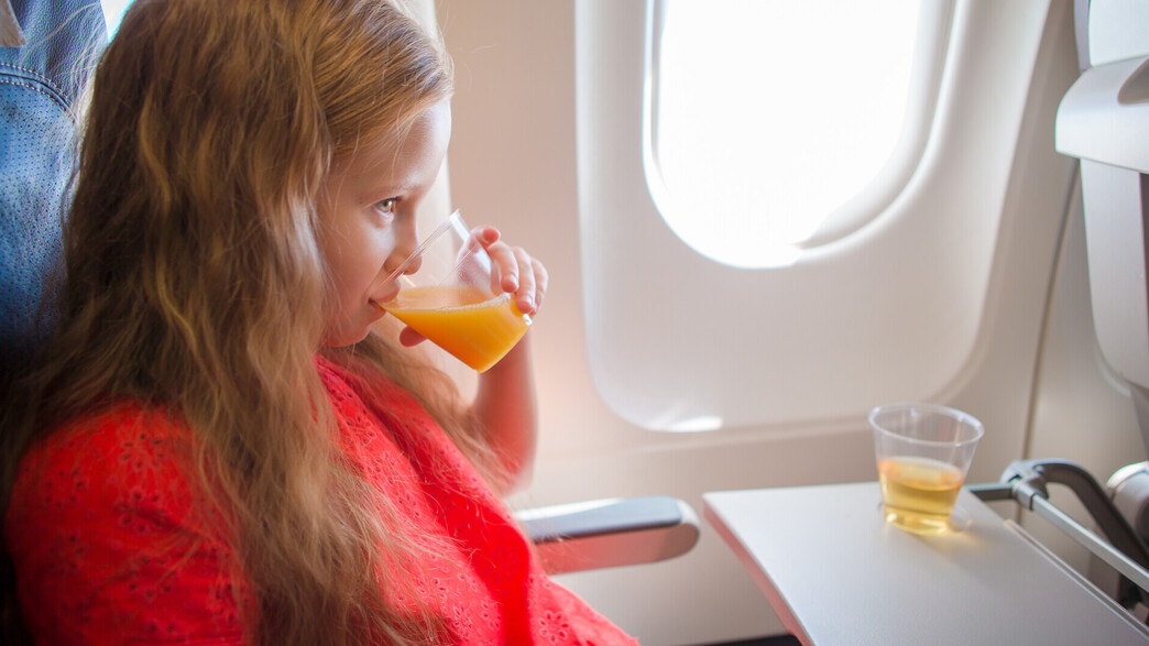 ילדה שותה מיץ תפוזים במטוס (צילום: TravnikovStudio, shutterstock)
