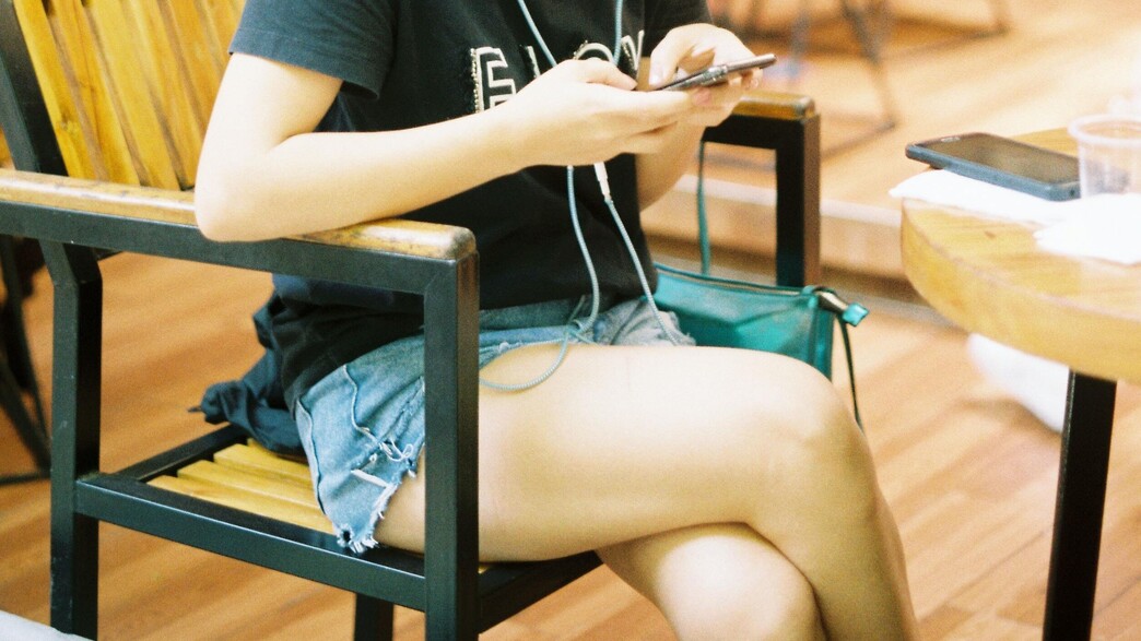 אישה יושבת רגל על רגל עם טלפון (צילום: unsplash)