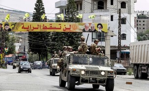 שיירת צבא ערבי על רקע דגלי חיזבאללה (צילום: Mahmoud ZAYYAT/AFP/GettyImages)