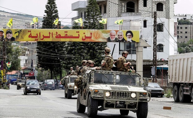 שיירת צבא ערבי על רקע דגלי חיזבאללה (צילום: Mahmoud ZAYYAT/AFP/GettyImages)