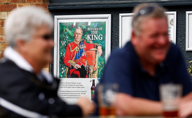 מבלים בפאב עם תמונת המלך צ'ארלס ברקע (צילום: רויטרס)
