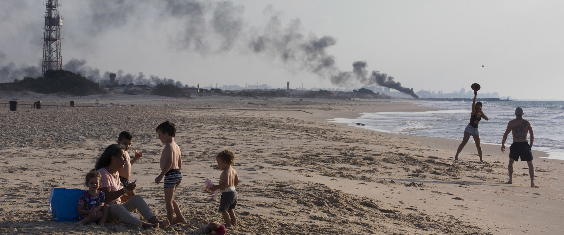 רוחצים בחוף זיקים, ברקע עשן מהמחאה ליד גדר הגבול עם עזה, 2018 (צילום: ap)
