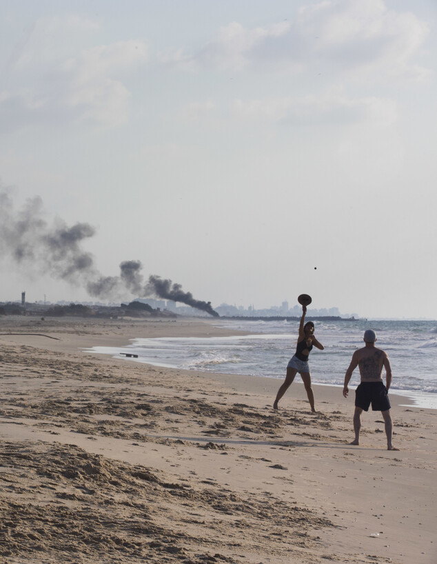 רוחצים בחוף זיקים, ברקע עשן מהמחאה ליד גדר הגבול עם עזה, 2018 (צילום: ap)