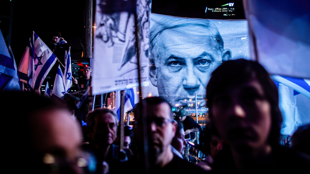 מפגינים נגד המהפכה המשפטית ומאחור תמונה של נתניהו