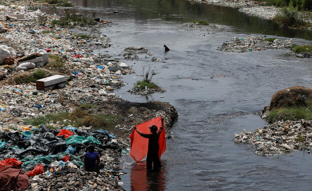 אדם שוטף פסולת פלסטיק בהודו (צילום: רויטרס)