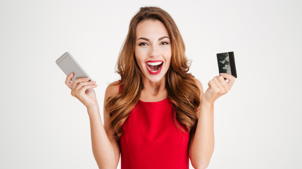 אישה מופתעת מחזיקה כרטיס אשראי מוגזם