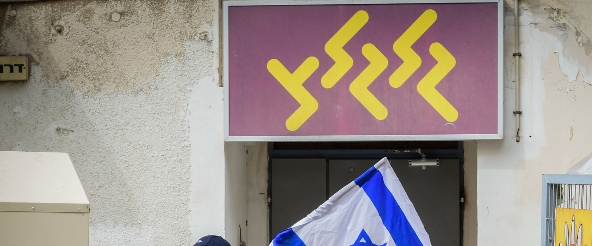 מפגין עם דגל ישראל מול משרדי גלגל