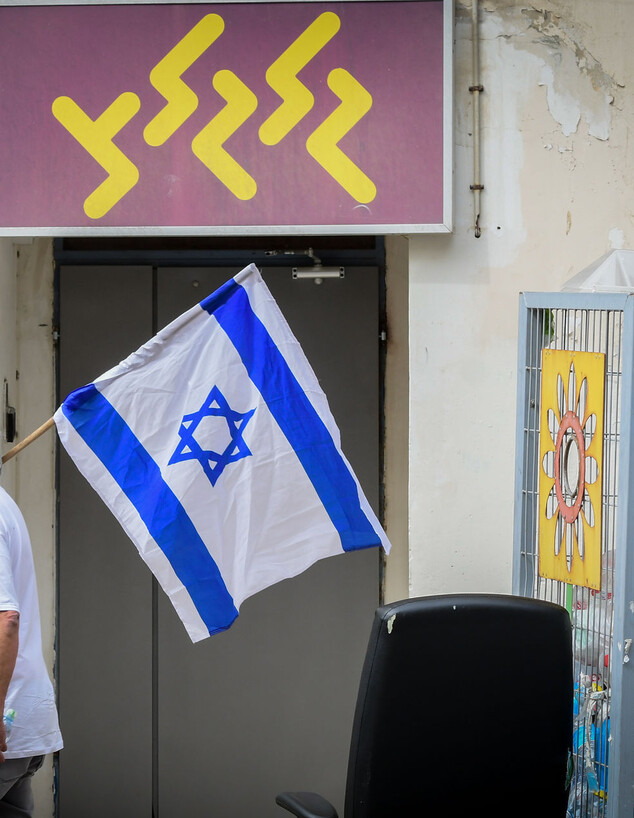 מפגין עם דגל ישראל מול משרדי גלגל
