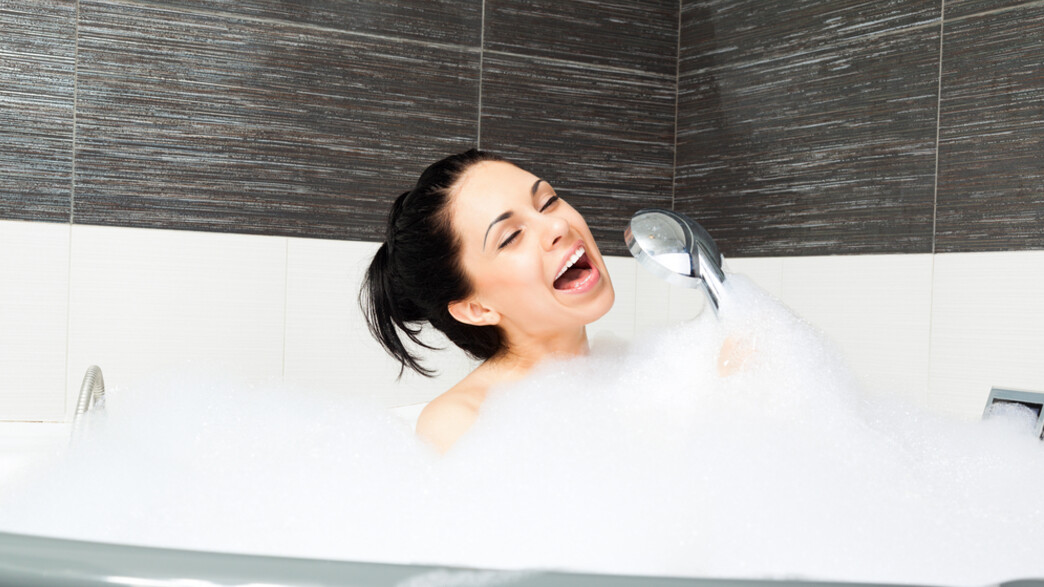 אישה מסתבנת במקלחת של בית מלון (צילום: Shutterstock)