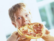 ילד בלונדיני אוכל פיצה עם נקניק (צילום: jupiter images)