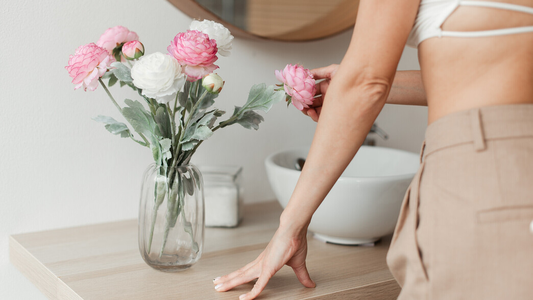 פרחים מלאכותיים באגרטל, אישה נוגעת בפרחים