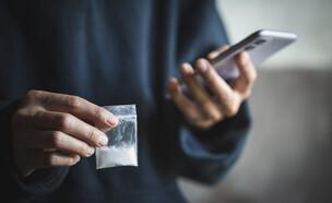 איש מחזיק טלפון, שקית קוקאין (צילום: Tinnakorn jorruang, shutterstock)