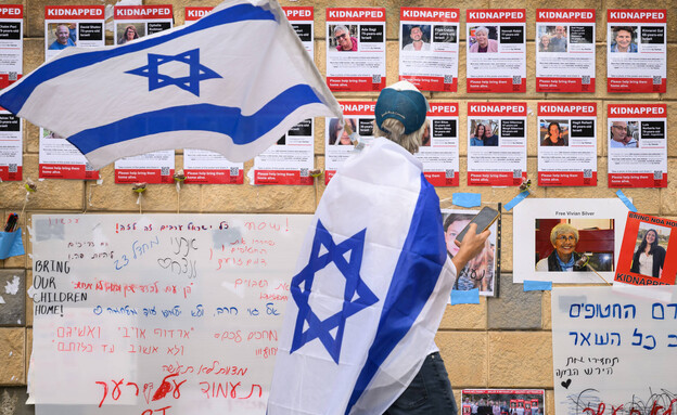אדם לצד פוסטרים של החטופים בתל אביב (צילום: Leon Neal/Getty Images)