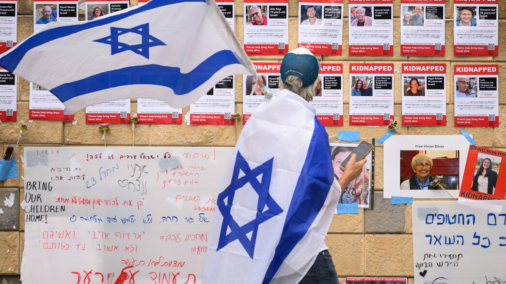 אדם לצד פוסטרים של החטופים בתל אביב (צילום: Leon Neal/Getty Images)