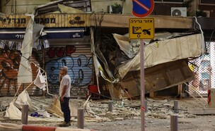 אדם עומד מול חנות בתל אביב שנפגעה מרקטה של חמאס, 7.10.23 (צילום: JACK GUEZ, AFP via Getty Images)
