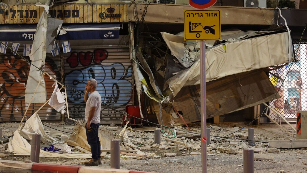 אדם עומד מול חנות בתל אביב שנפגעה מרקטה של חמאס, 7.10.23 (צילום: JACK GUEZ, AFP via Getty Images)