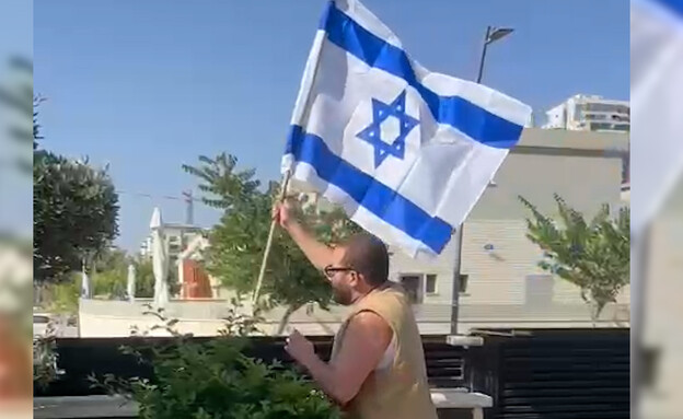 אליאב זוהר תולה דגל במרפסת ביתו (צילום: מתוך 