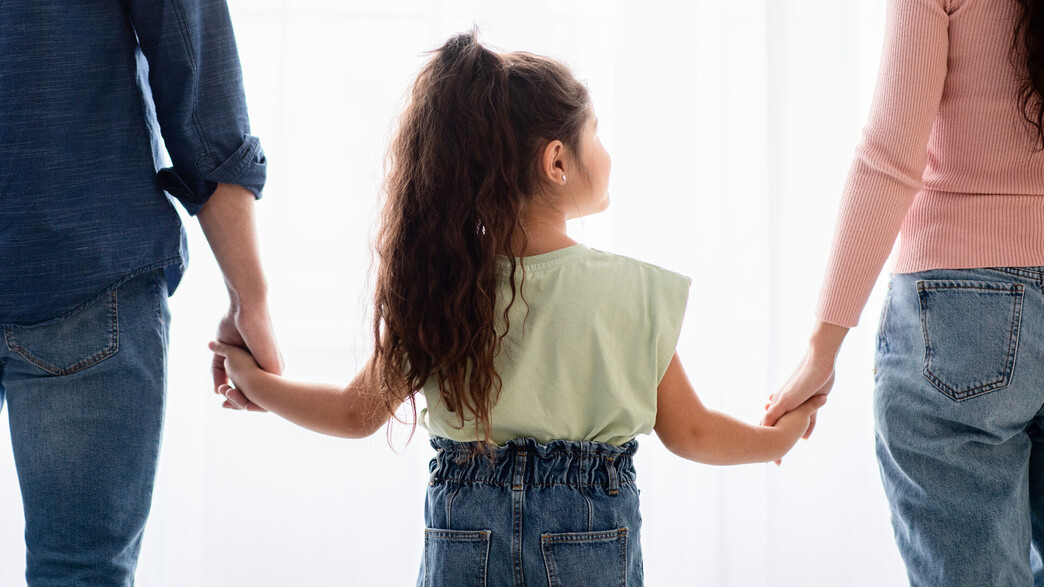 זוג הורים וילדה מחזיקים ידיים