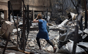 תושבת מבוא מודיעים בוחנת את ההרס לאחר השריפה, 2019 (צילום: הדס פרוש, פלאש 90)