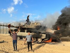 פלסטינים חוגגים סביב טנק צה"ל שהותקף ב-7 באוקטובר (צילום: רויטרס)