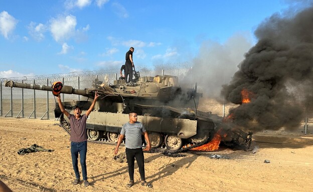 פלסטינים חוגגים סביב טנק צה"ל שהותקף ב-7 באוקטובר (צילום: רויטרס)