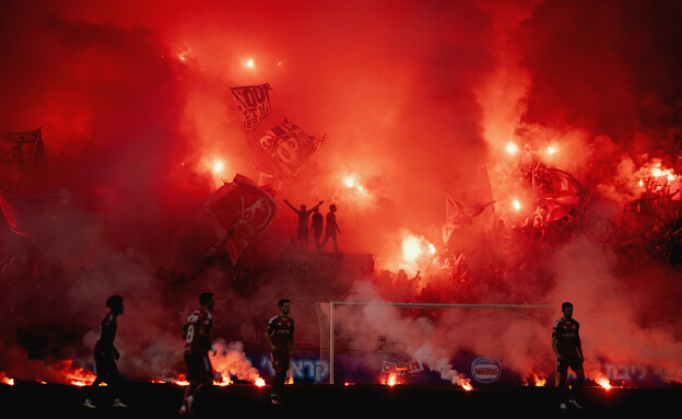 שער חמש באצטדיון בלומפילד עפוף עשן ואבוקות בעת משח (צילום: יובל דניאל)