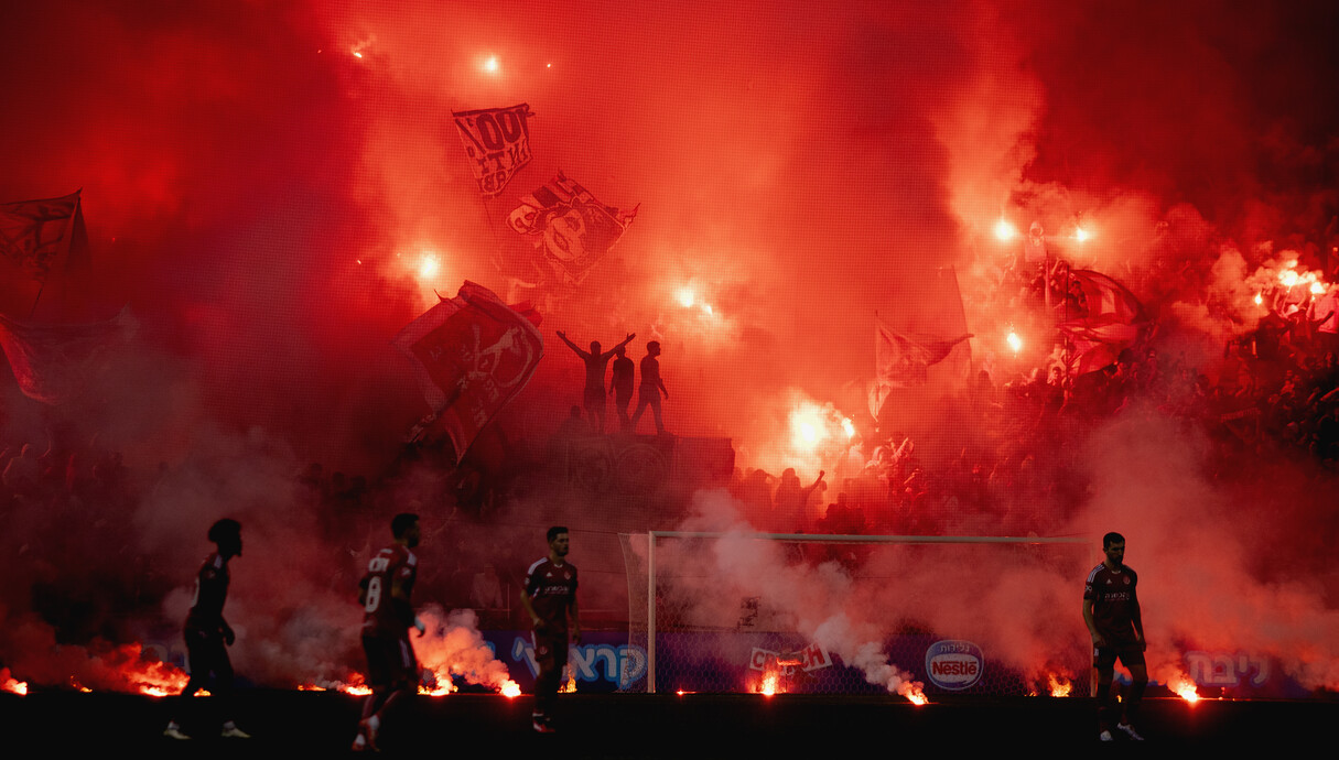 שער חמש באצטדיון בלומפילד עפוף עשן ואבוקות בעת משח (צילום: יובל דניאל)