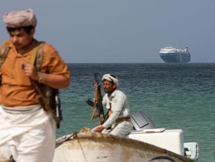 מורדים חות'ים על רקע הספינה גלקסי לידר שנחטפה (צילום: רויטרס)