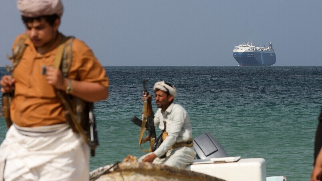 מורדים חות'ים על רקע הספינה גלקסי לידר שנחטפה (צילום: רויטרס)