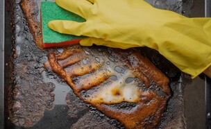 יד מנקה תבנית אפייה מלוכלכת, תבנית אפיה (צילום: Leka Sergeeva, SHUTTERSTOCK)