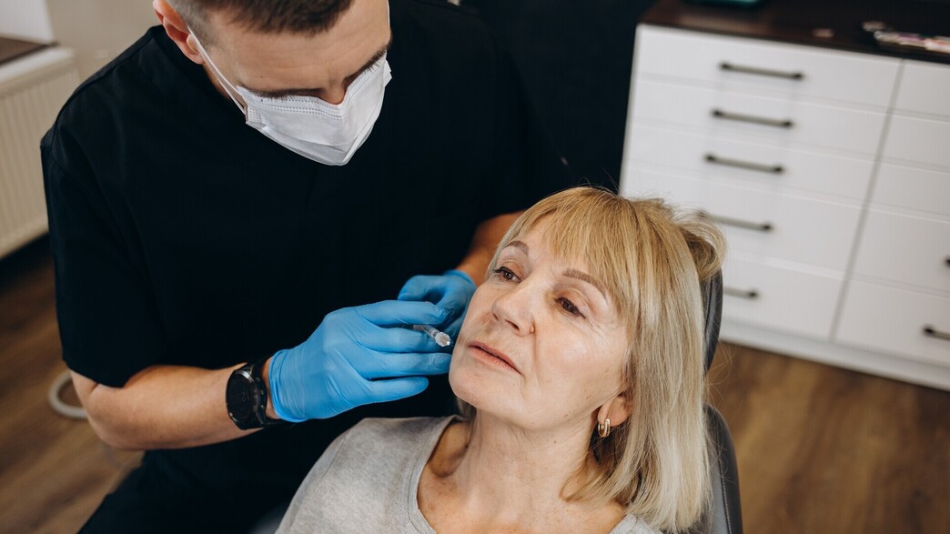 רופא מזריק בוטוקס לאישה מבוגרת