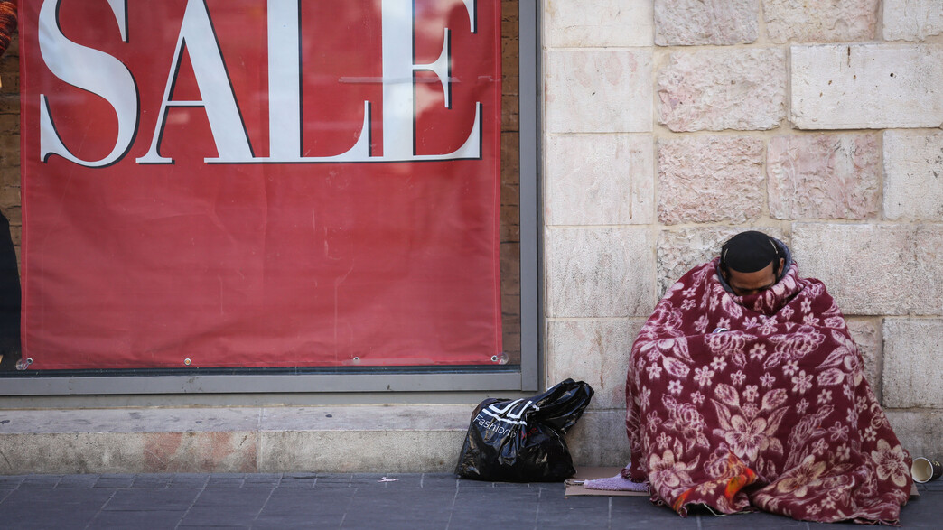 חסר בית מתחמם עם שמיכה בפתח חנות בירושלים (צילום: נתי שוחט, יונתן זינדל, רועי אלימה, פלאש 90)