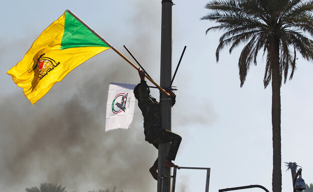 מפגין מניף בעיראק דגל של גדודי חיזבאללה בעיראק (צילום: רויטרס)